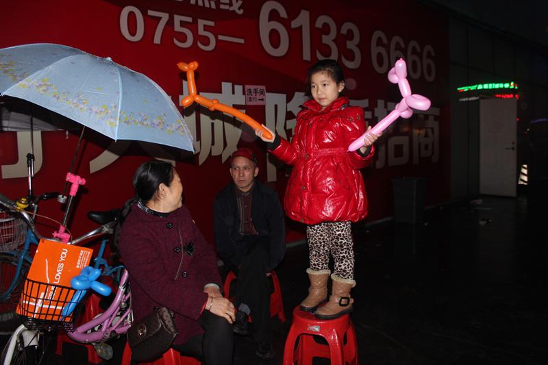 可爱的小女孩站在凳子上远远观看节目，挥舞着手中的气球。（图：基督时报/施迦南）