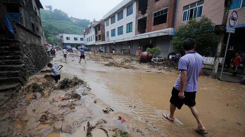 6月10日，在贵州凯里市舟溪镇，出现特大暴雨，引发泥石流灾害，人们行走在被泥石流冲过的街头。（图：新华网）