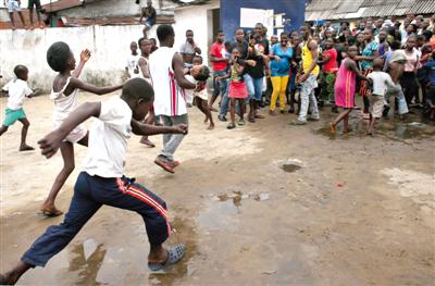 8月16日，利比里亚首都蒙罗维亚，一名男子抱着一个女孩从一个埃博拉隔离区中跑出